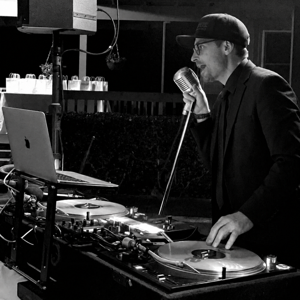 nate burgoyne in a luxury suit at the turntables with MC mic